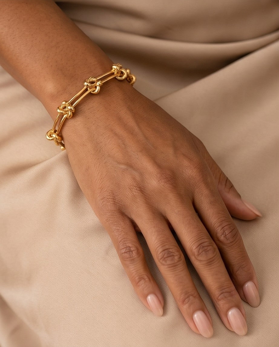 Ennvy Accessories Poised Bracelet in polished gold-plated stainless steel with knot detailing and lobster clasp.